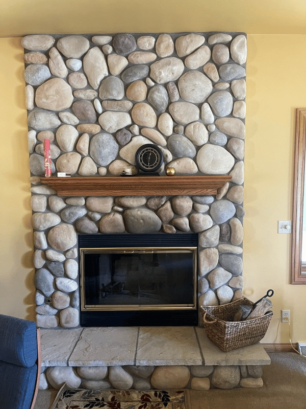 A fireplace before restoration, showing worn or outdated surroundings and finish