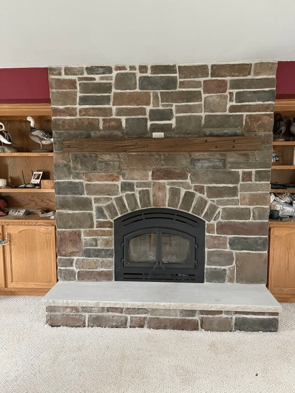 A clean, renovated fireplace with a polished surround and hearth after professional chimney service