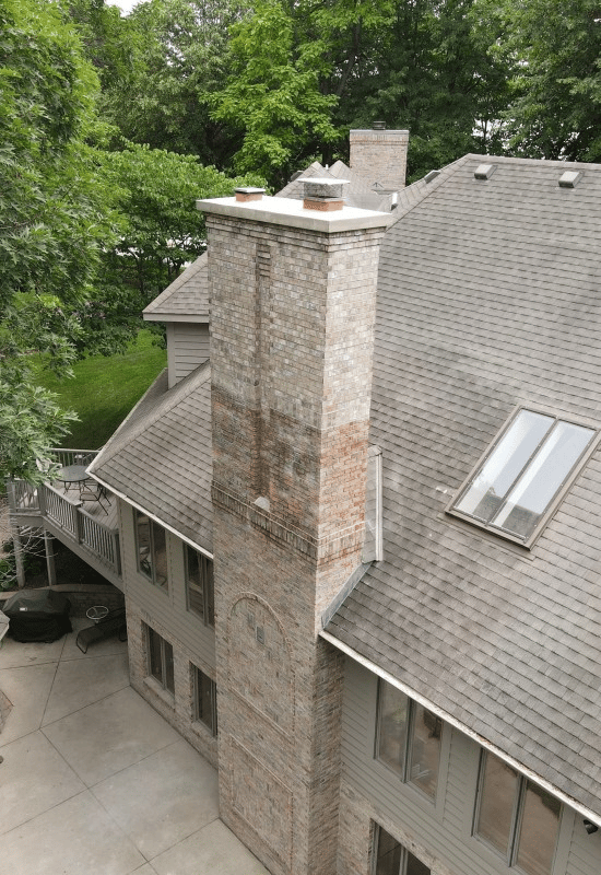 A newly rebuilt brick chimney on a rooftop, showing clean mortar joints and restored brickwork after repair.